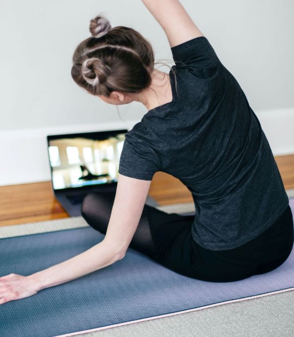 Woman stretching in front of a laptop, photo by Kari Shea